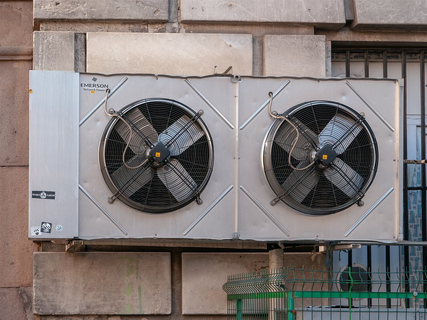 Condensadora de dos ventiladores fijada a la fachada de un edificio